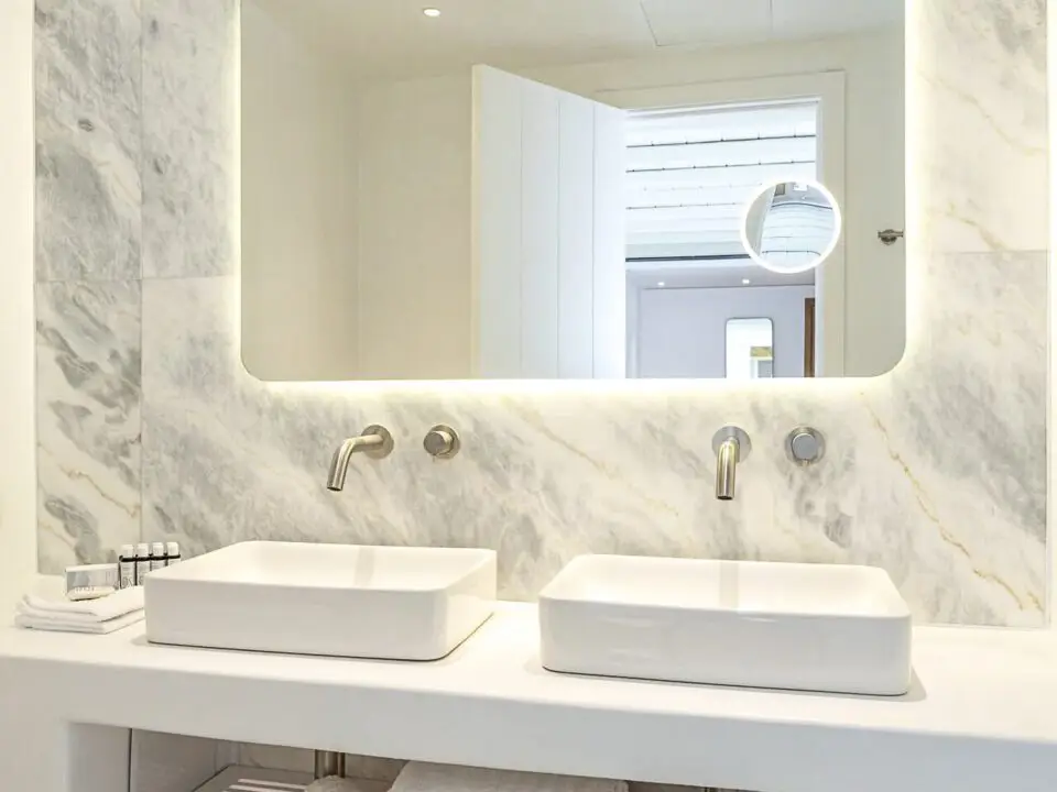 Exclusive Suite with Outdoor Hot Tub: Modern marble bathroom vanity with two vessel sinks and a backlit mirror