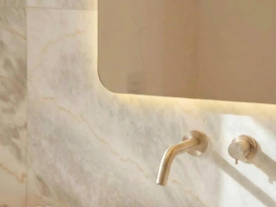 Exclusive Suite with Outdoor Hot Tub: Modern bathroom sink with wall-mounted faucet, marble wall, and backlit mirror
