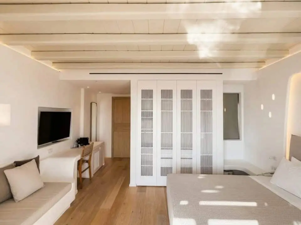 Junior Suite with Outdoor Hot Tub: Bright minimalist bedroom with a sofa, wall-mounted TV, desk, and a bed separated by a white slatted partition
