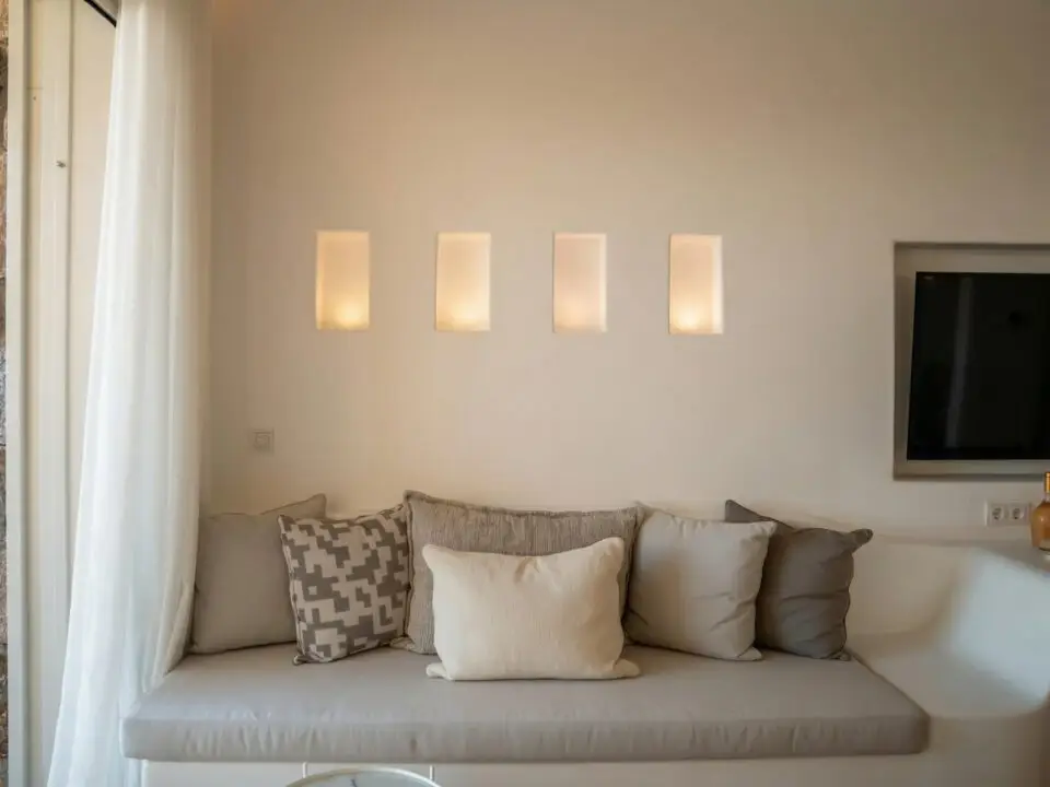 Junior Suite with Outdoor Hot Tub: Built-in window seat with cushions and pillows beneath wall lights, beside a wall-mounted TV