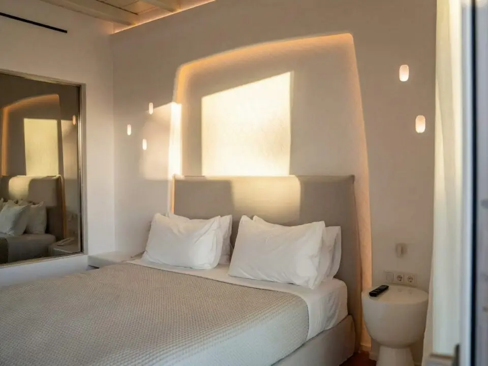 Junior Suite with Outdoor Hot Tub: Modern bedroom with a king-sized bed, white pillows, and warm recessed lighting