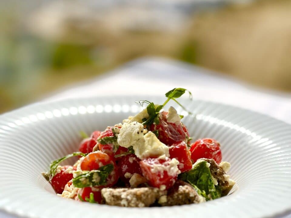 Nomia Mykonos Sunset Suites Menu: Tomato and Mykonian cheese green salad in a white bowl