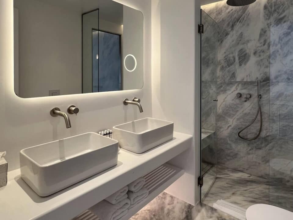 Junior Suite with Private Heated Swimming Pool: Modern bathroom with double sinks, illuminated mirror, and marble shower enclosure