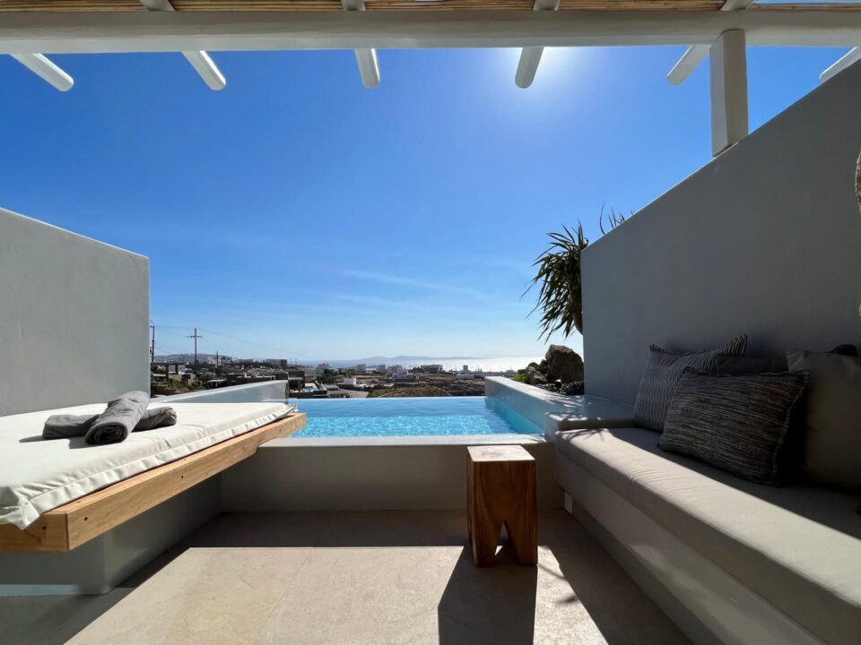 Junior Suite with Private Heated Swimming Pool: Modern patio with lounge seating and a private pool overlooking the sea under a clear blue sky