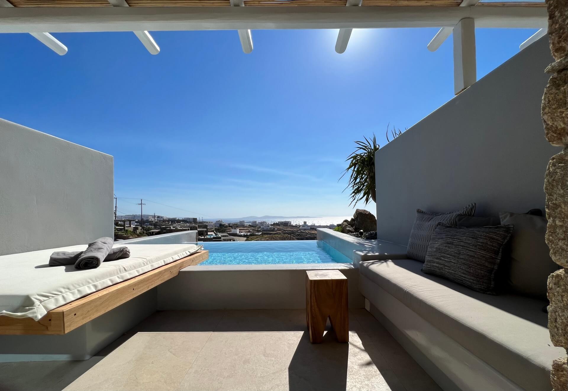 Junior Suite with Private Heated Swimming Pool: Modern patio with lounge seating and a private pool overlooking the sea under a clear blue sky