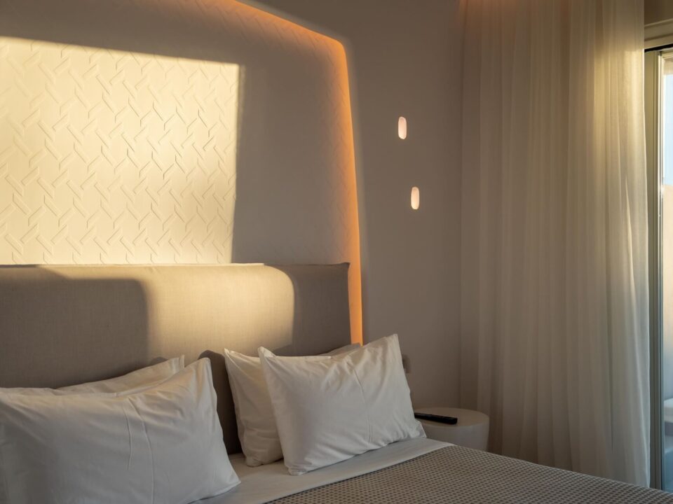 Junior Suite with Private Heated Swimming Pool: Sunlit bedroom with a bed, white pillows, sheer curtains, and a window view