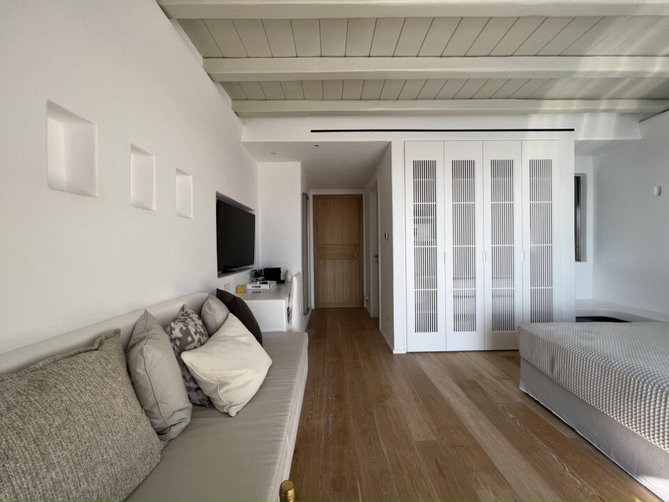 Junior Suite with Private Heated Swimming Pool: Modern bedroom with white walls, wood floor, sofa, TV, and built-in closet