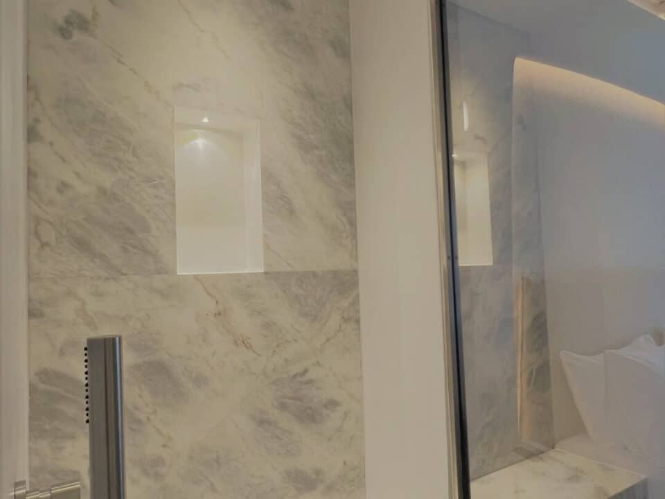 Junior Suite with Private Heated Swimming Pool: Marble-tiled shower with a built-in bench, rain showerhead, and window