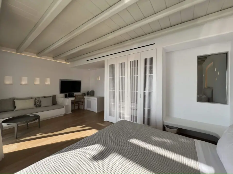 Premium Suite with Private Heated Swimming Pool: Modern bedroom with white built-in closets, a desk, sofa, and sunlight on the floor