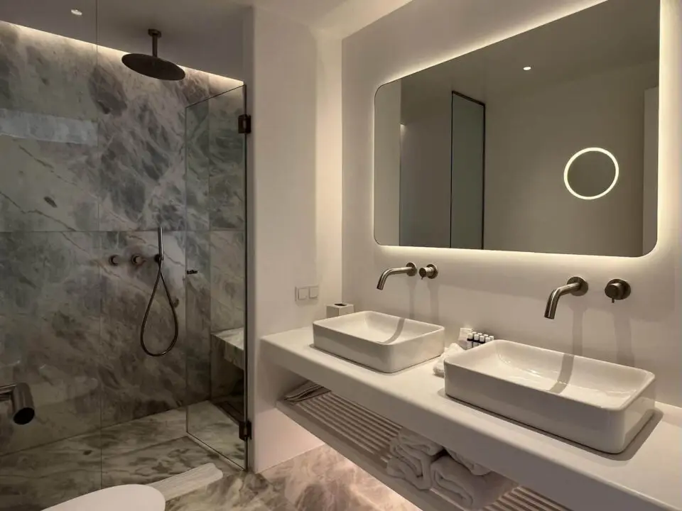 Premium Suite with Private Heated Swimming Pool: Modern bathroom with double sinks, large illuminated mirror, and glass shower enclosure