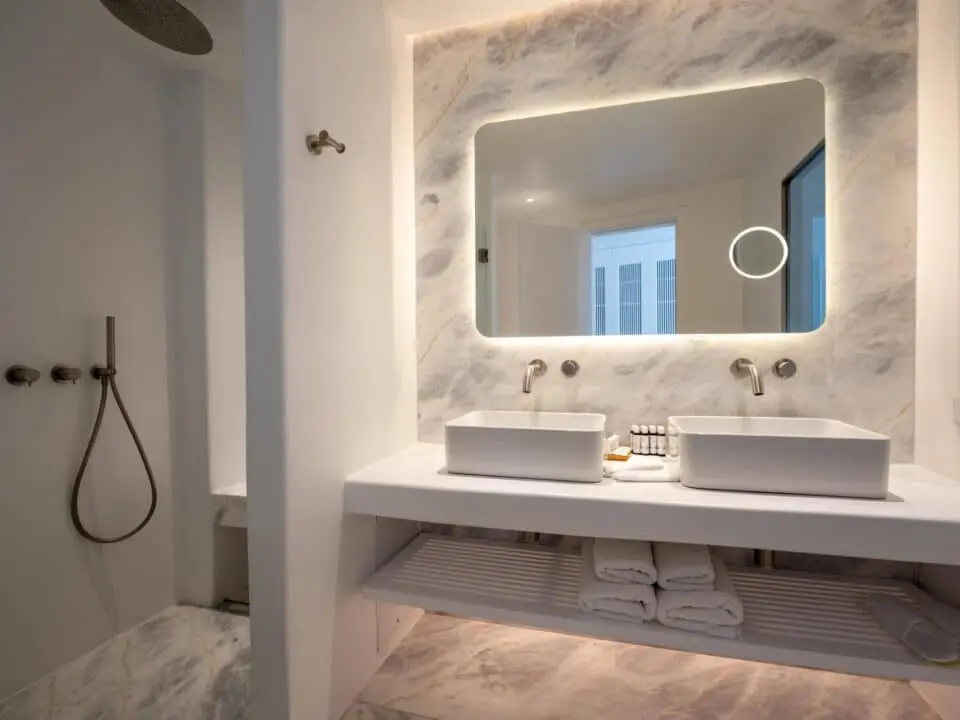 Premium Suite with Private Heated Swimming Pool: Modern bathroom with double sinks, backlit mirror, and marble finishes