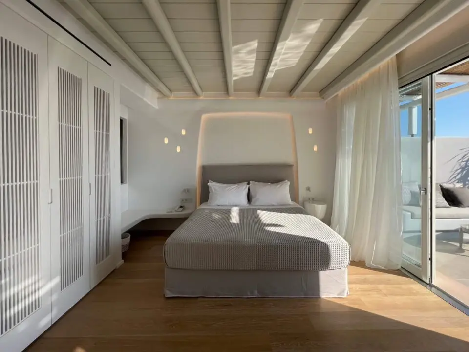 Premium Suite with Private Heated Swimming Pool: Bright minimalist bedroom with a king-sized bed, built-in wardrobes, and a sliding glass door to a sunlit terrace