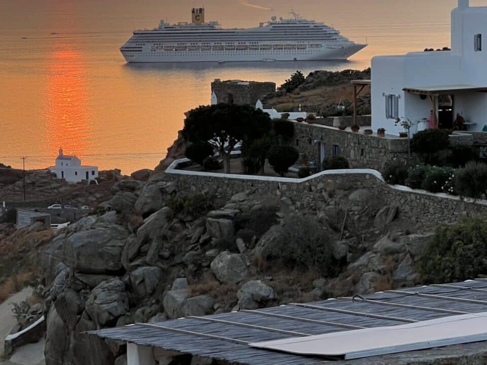 Nomia Mykonos Sunset Suites: Sunset over the sea with a cruise ship near Mykonos and the Nomia Sunset Suites sign in the foreground