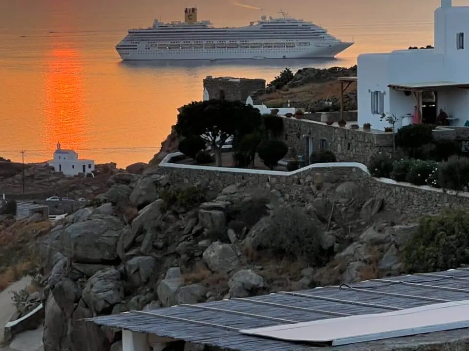 Nomia Mykonos Sunset Suites: Sunset over the sea with a cruise ship near Mykonos and the Nomia Sunset Suites sign in the foreground