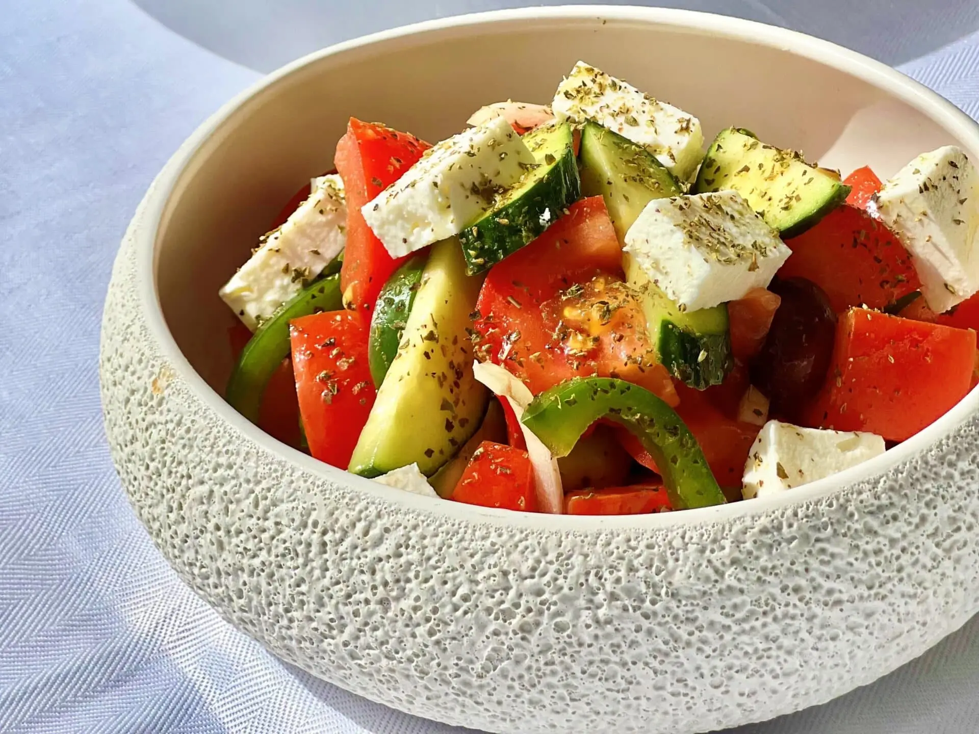Nomia Mykonos Sunset Suites Menu: Greek salad with tomatoes, cucumber, green pepper, olives, and feta cheese in a bowl