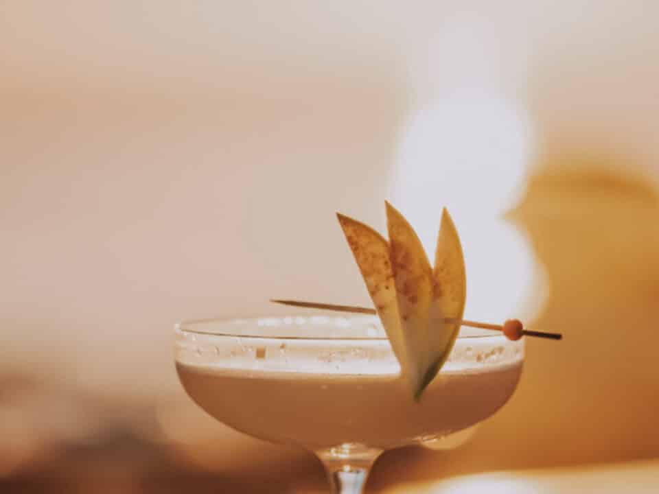 Nomia Mykonos Sunset Suites Bar: Martini Cocktail in a coupe glass garnished with sliced fruit and a skewer