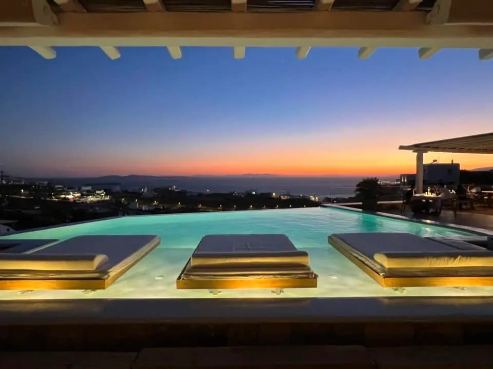 Nomia Mykonos Sunset Suites: Infinity pool with lounge beds overlooking the sea at sunset