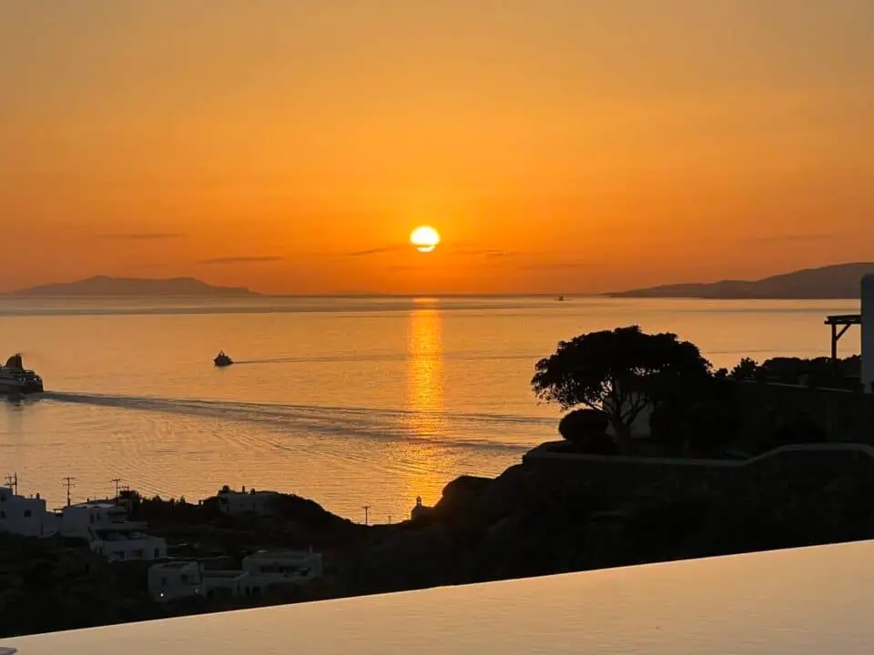 Nomia Mykonos Sunset Suites View: Sunset over the sea with two boats and a golden reflection on the water