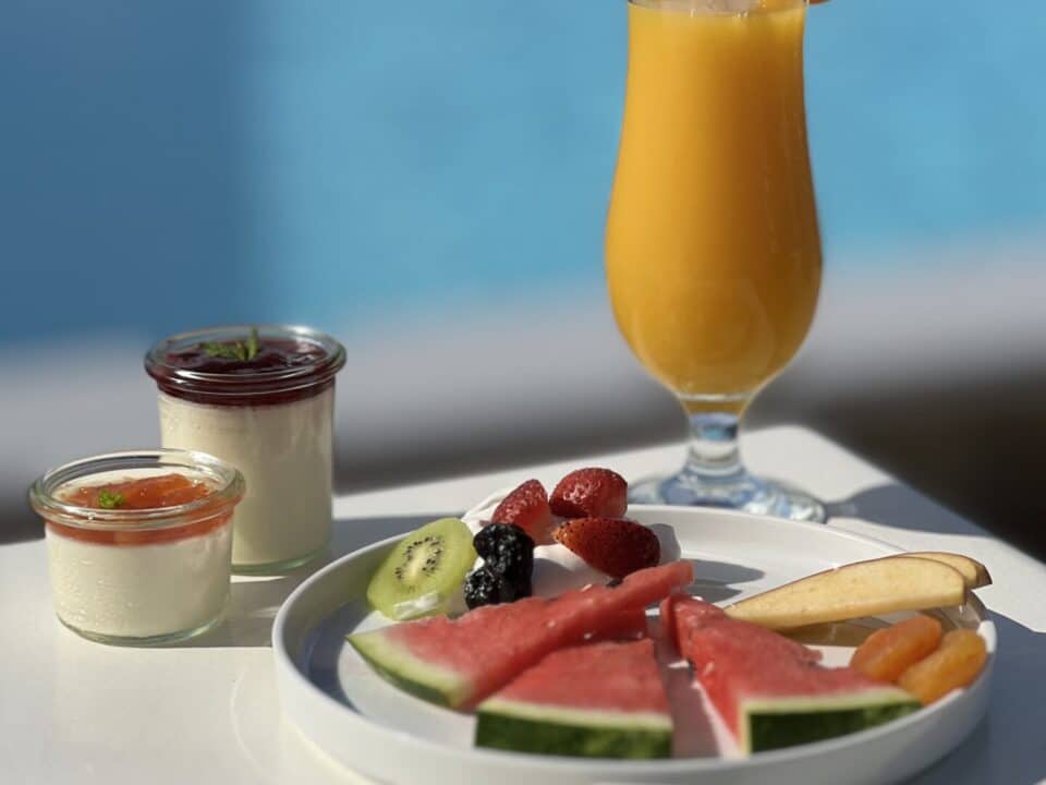 Nomia Mykonos Sunset Suites Restaurant: Breakfast spread with orange juice, fruit, and yogurt by a pool