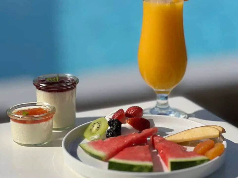 Nomia Mykonos Sunset Suites Restaurant: Breakfast spread with orange juice, fruit, and yogurt by a pool