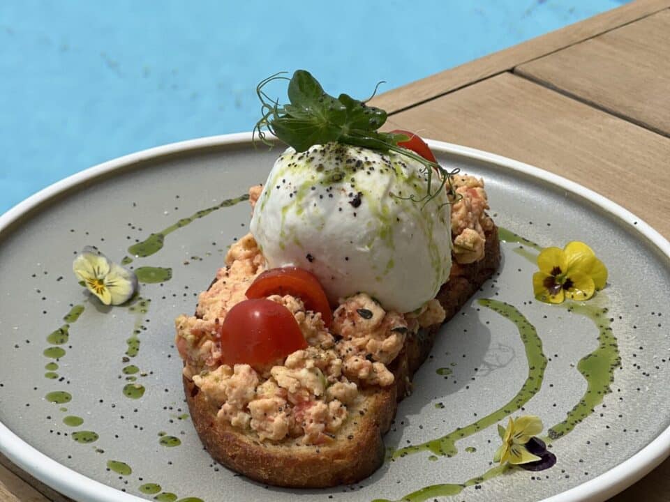 Nomia Mykonos Sunset Suites Restaurant: Gourmet toast topped with burrata, cherry tomatoes, and herbs, served by the infinity pool