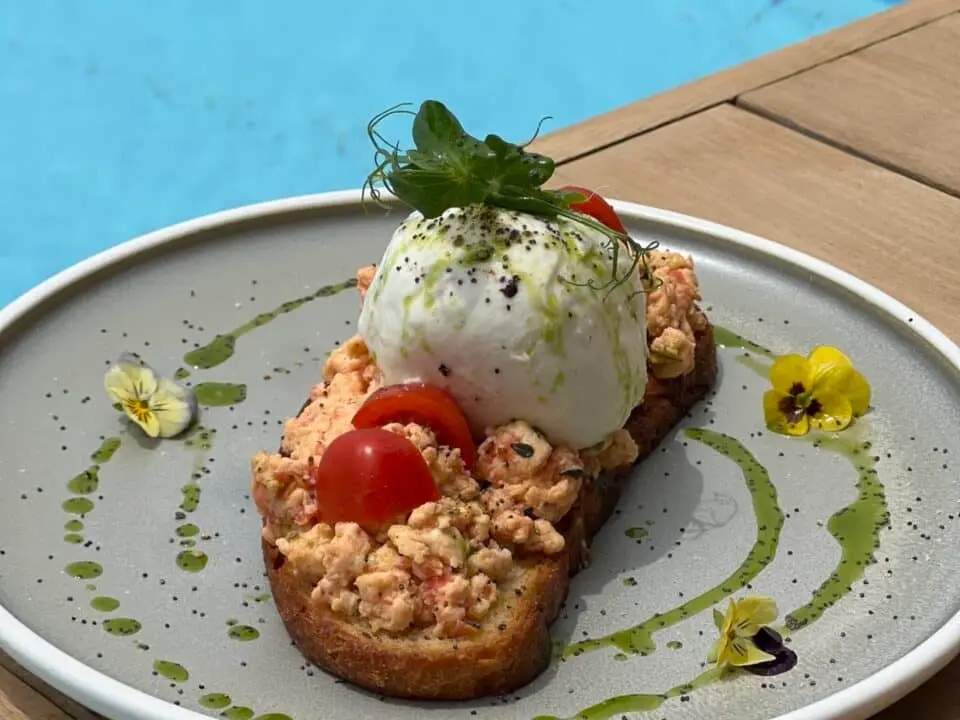 Nomia Mykonos Sunset Suites Restaurant: Gourmet toast topped with burrata, cherry tomatoes, and herbs, served by the infinity pool